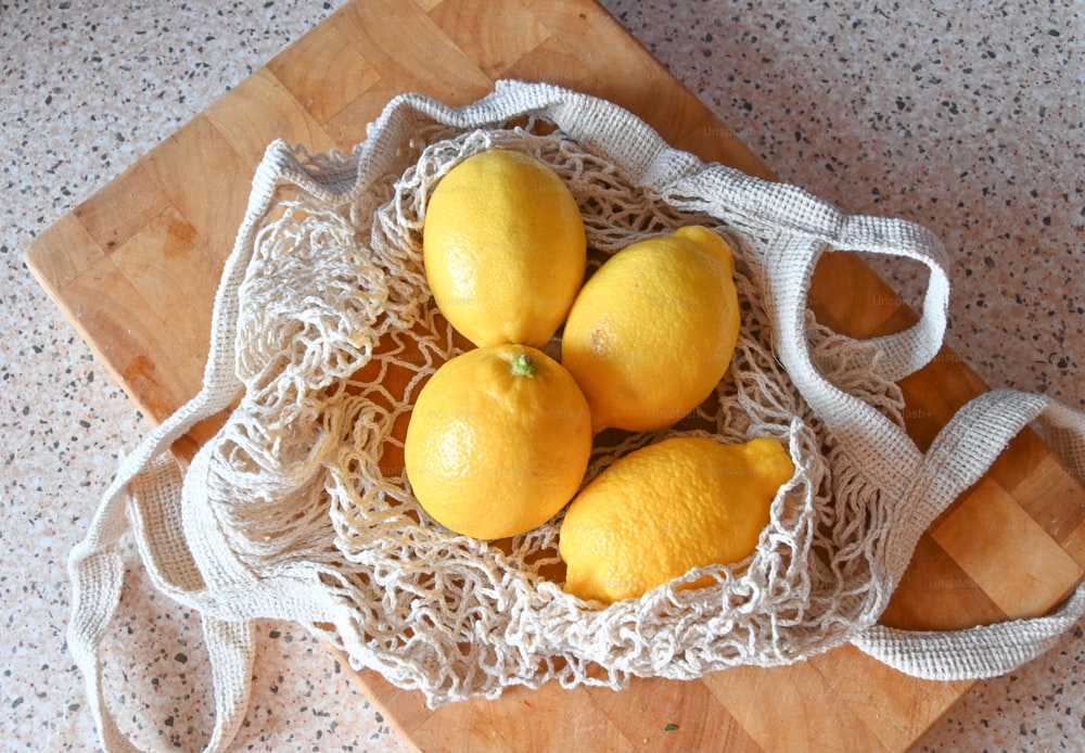 a bunch of lemons in a bag on a cutting board