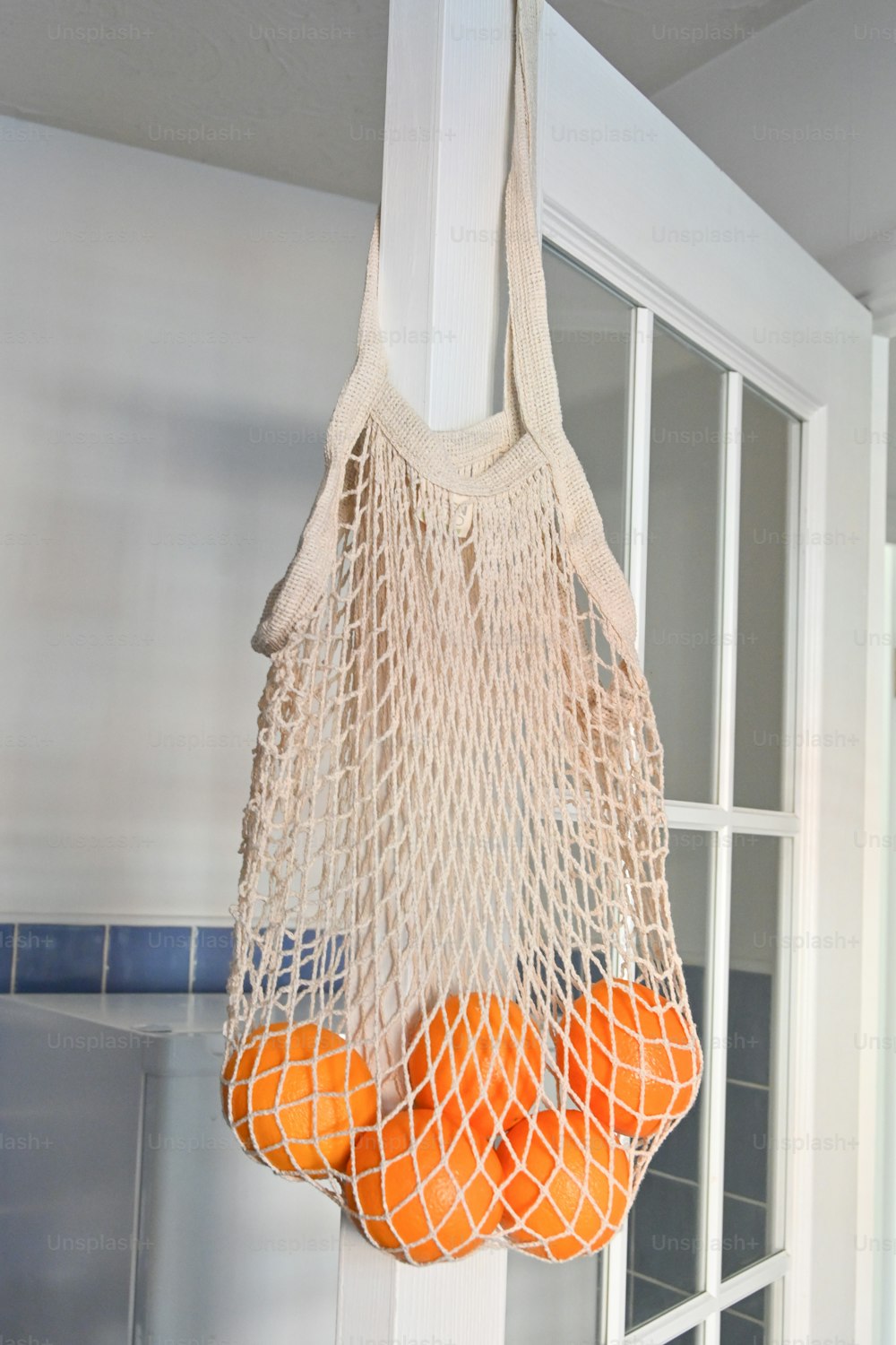 a bag of oranges hanging from a hook