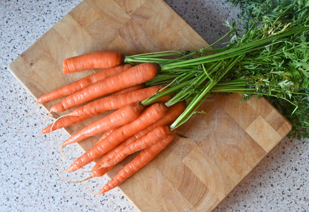 un mazzo di carote sedute su un tagliere