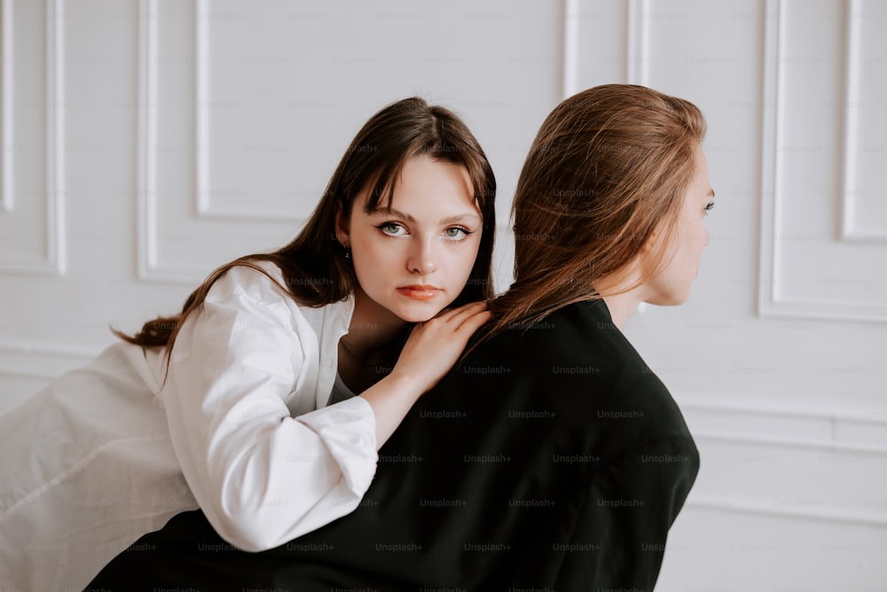 two women are sitting down and one is holding the other