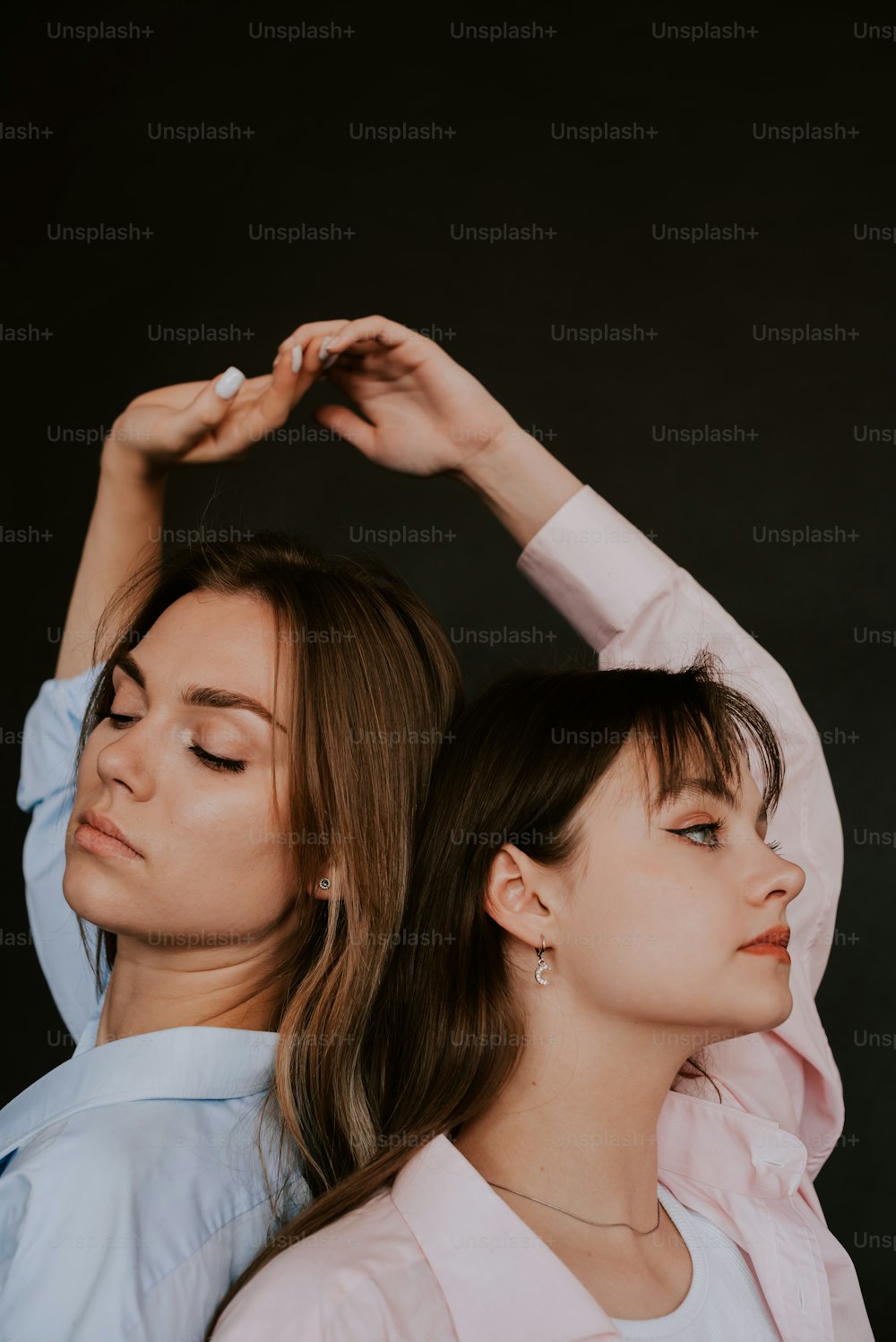 two women standing next to each other in front of a black background