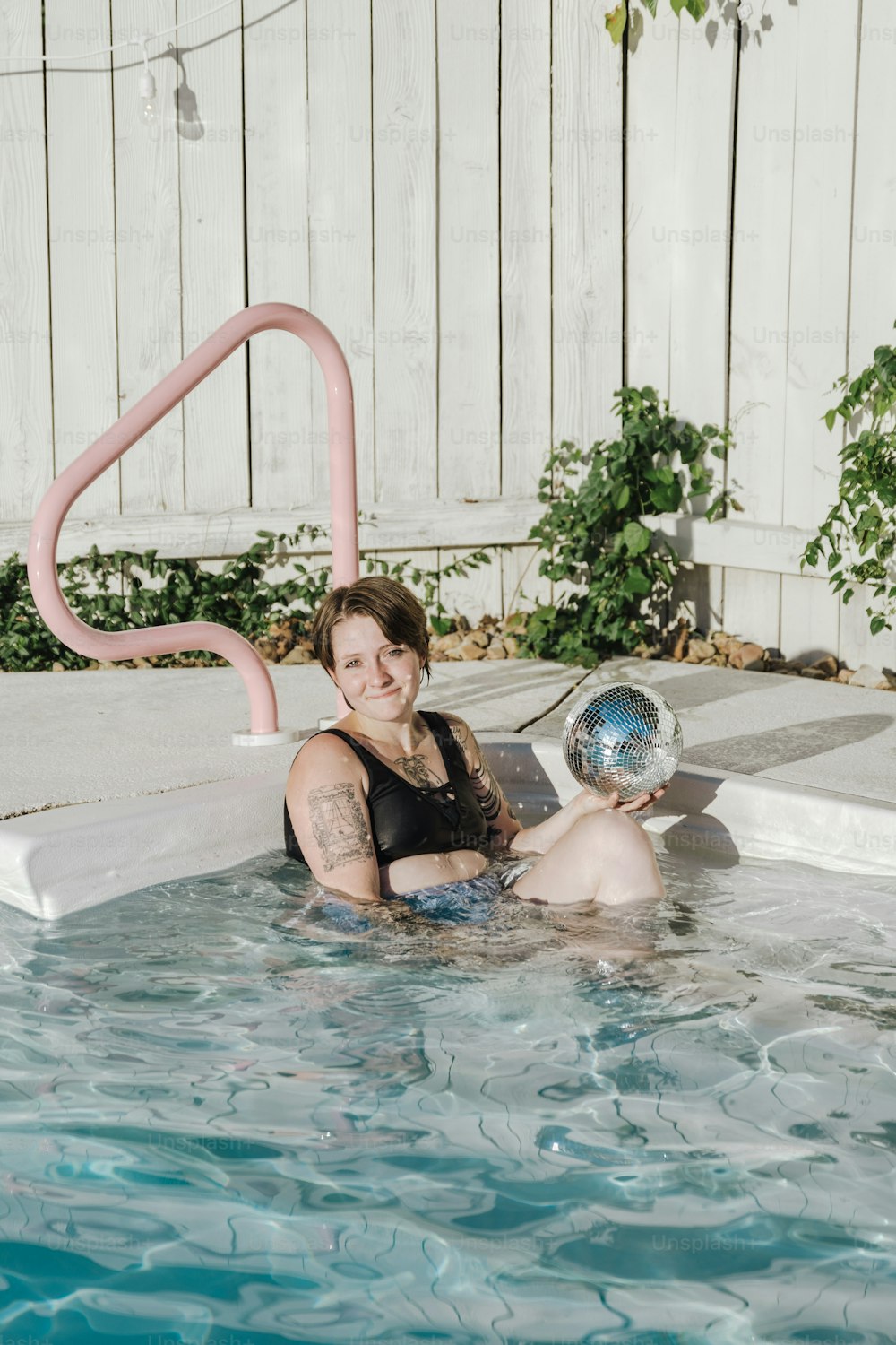 a woman sitting in a pool with a ball in her hand