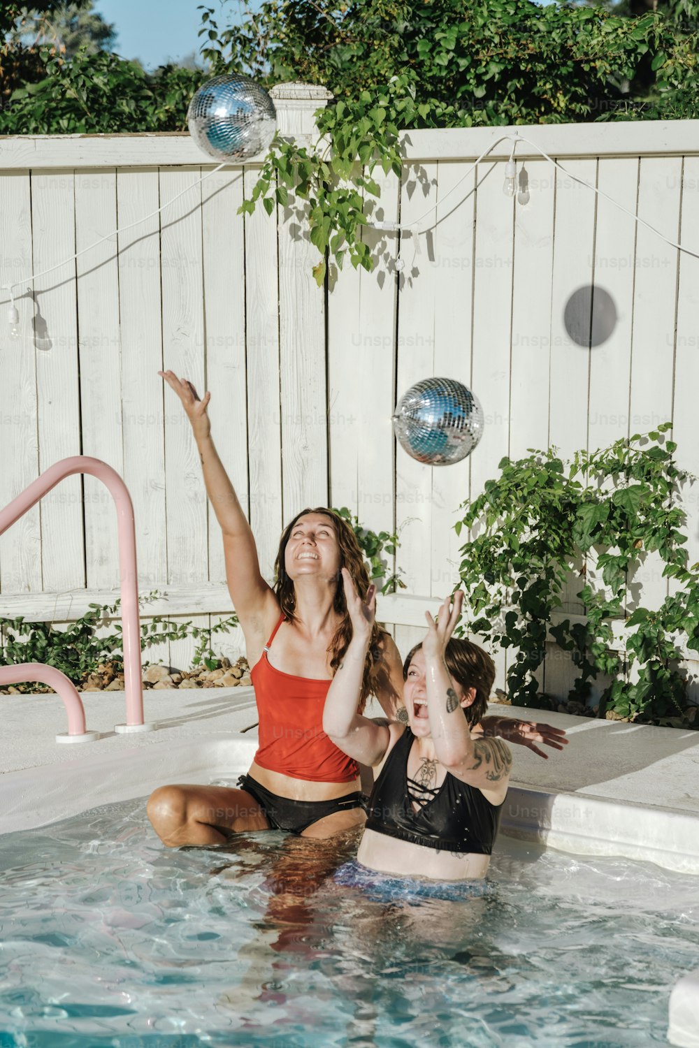 two women in a pool playing with a ball