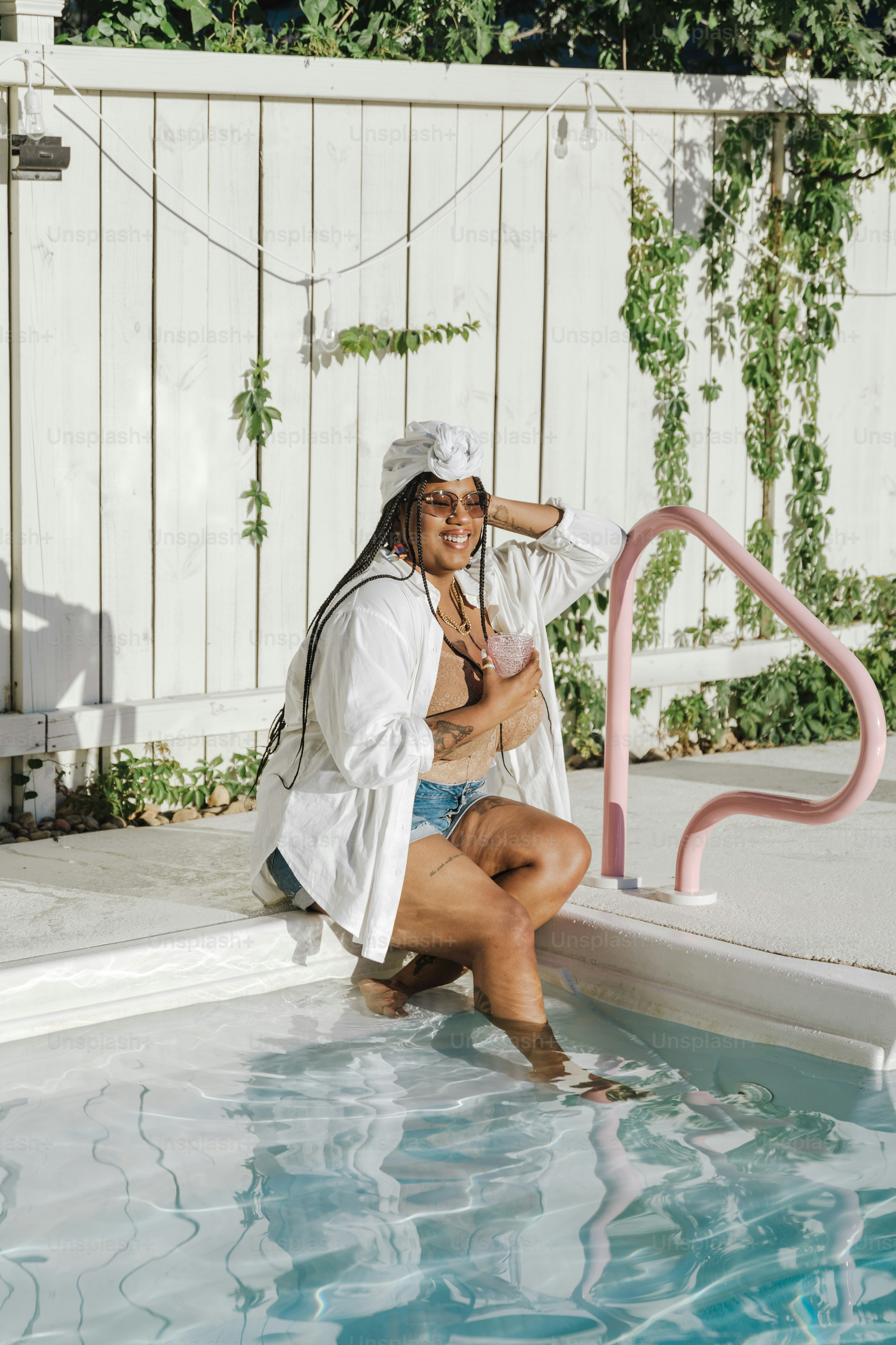 uma mulher sentada em uma piscina com uma toalha na cabeça
