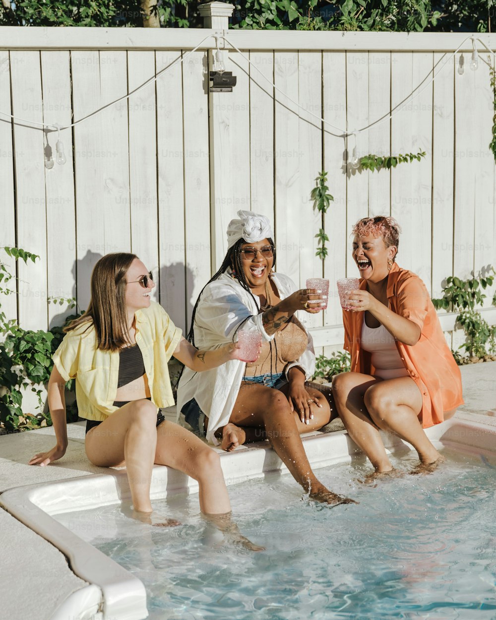 a group of women sitting around a swimming pool