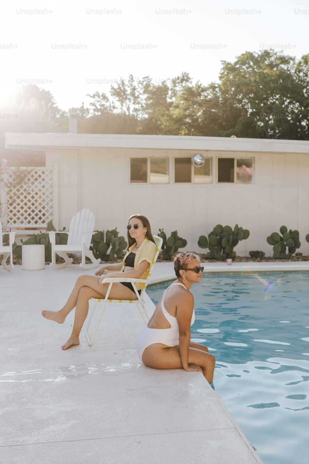 a couple of women sitting next to a swimming pool