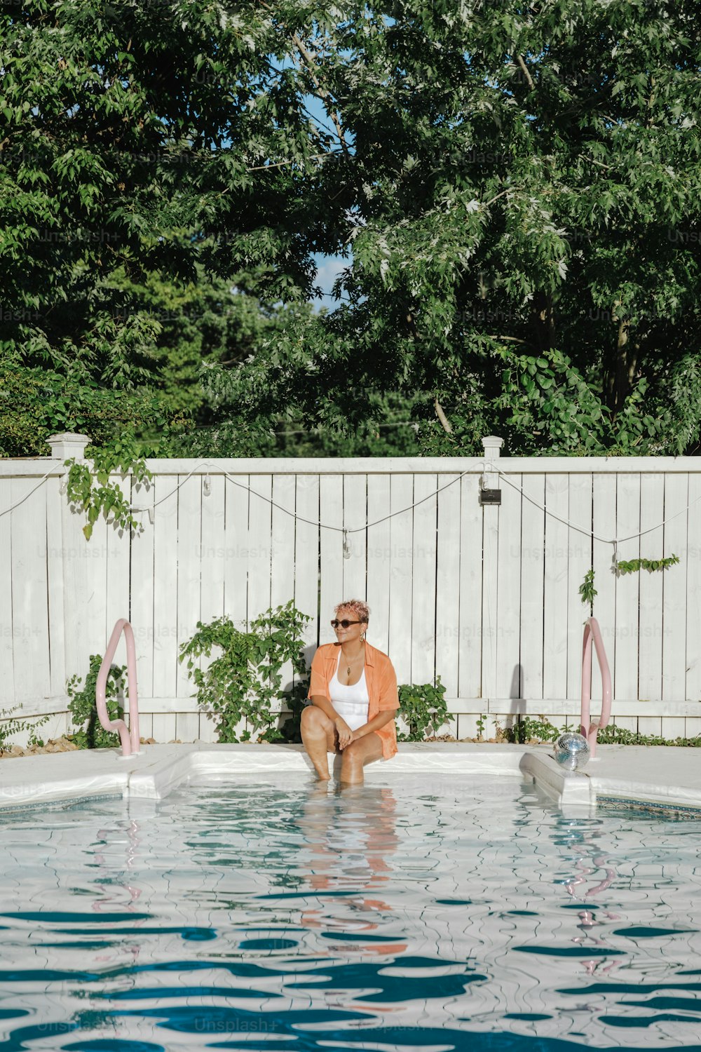 a woman sitting on the edge of a pool