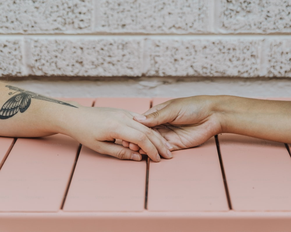 Eine Person mit einem Tattoo auf dem Arm, die auf einer rosa Bank sitzt