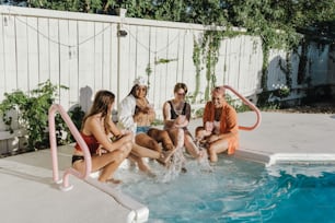 a group of young women sitting around a pool