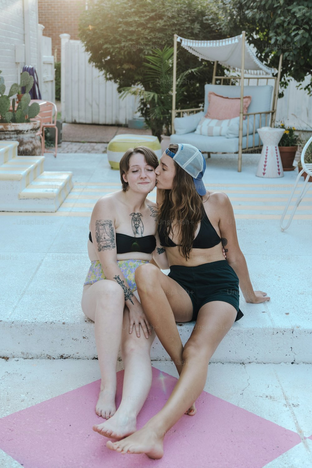 two women sitting on the steps of a pool