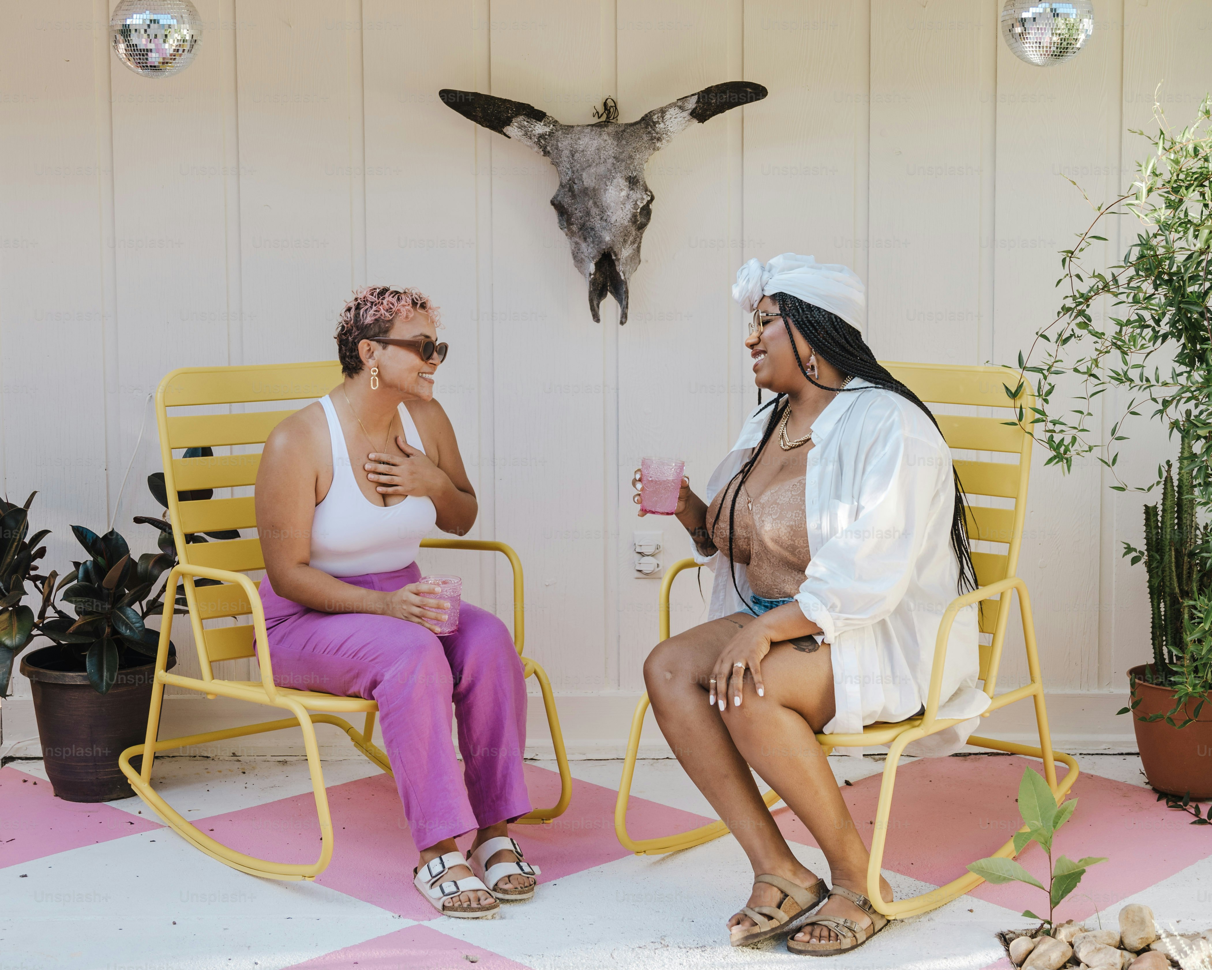 a couple of women sitting on top of yellow chairs