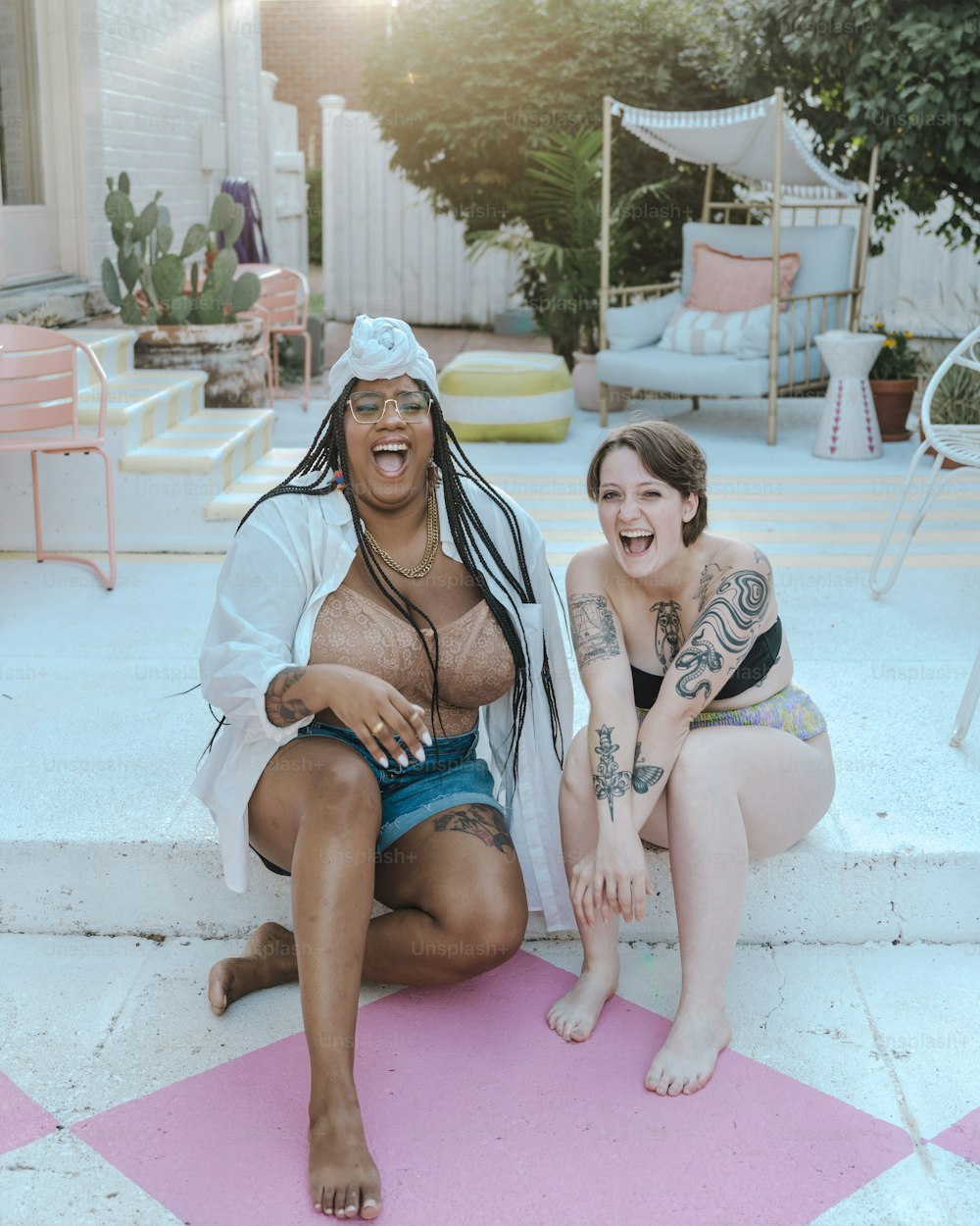 a couple of women sitting on top of a pink mat
