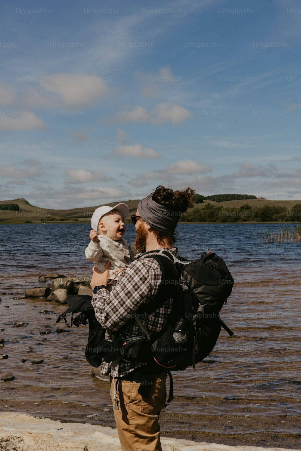 a man holding a baby while standing next to a body of water