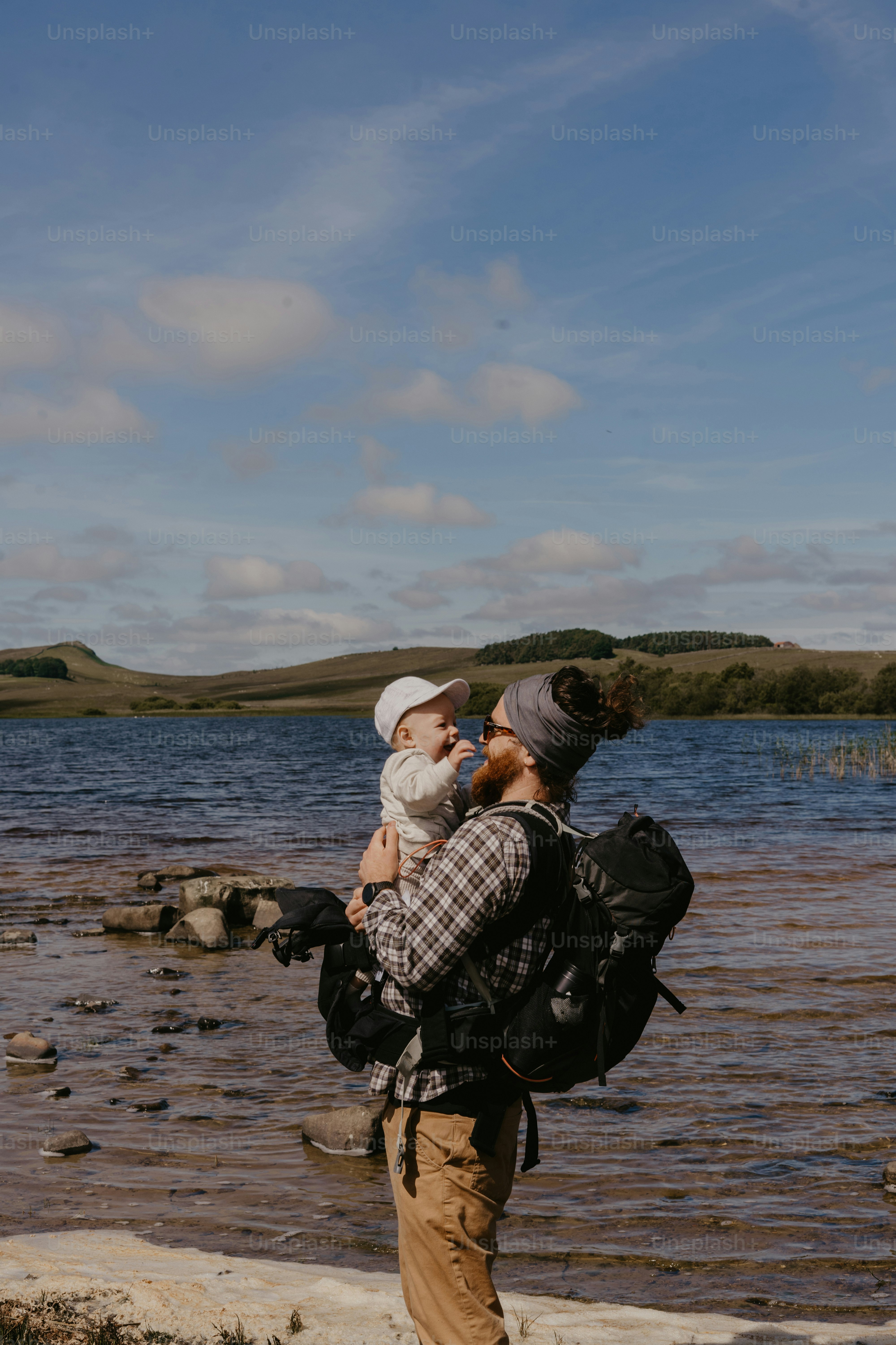 a man holding a baby while standing next to a body of water
