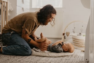 a man holding a baby while sitting on the floor