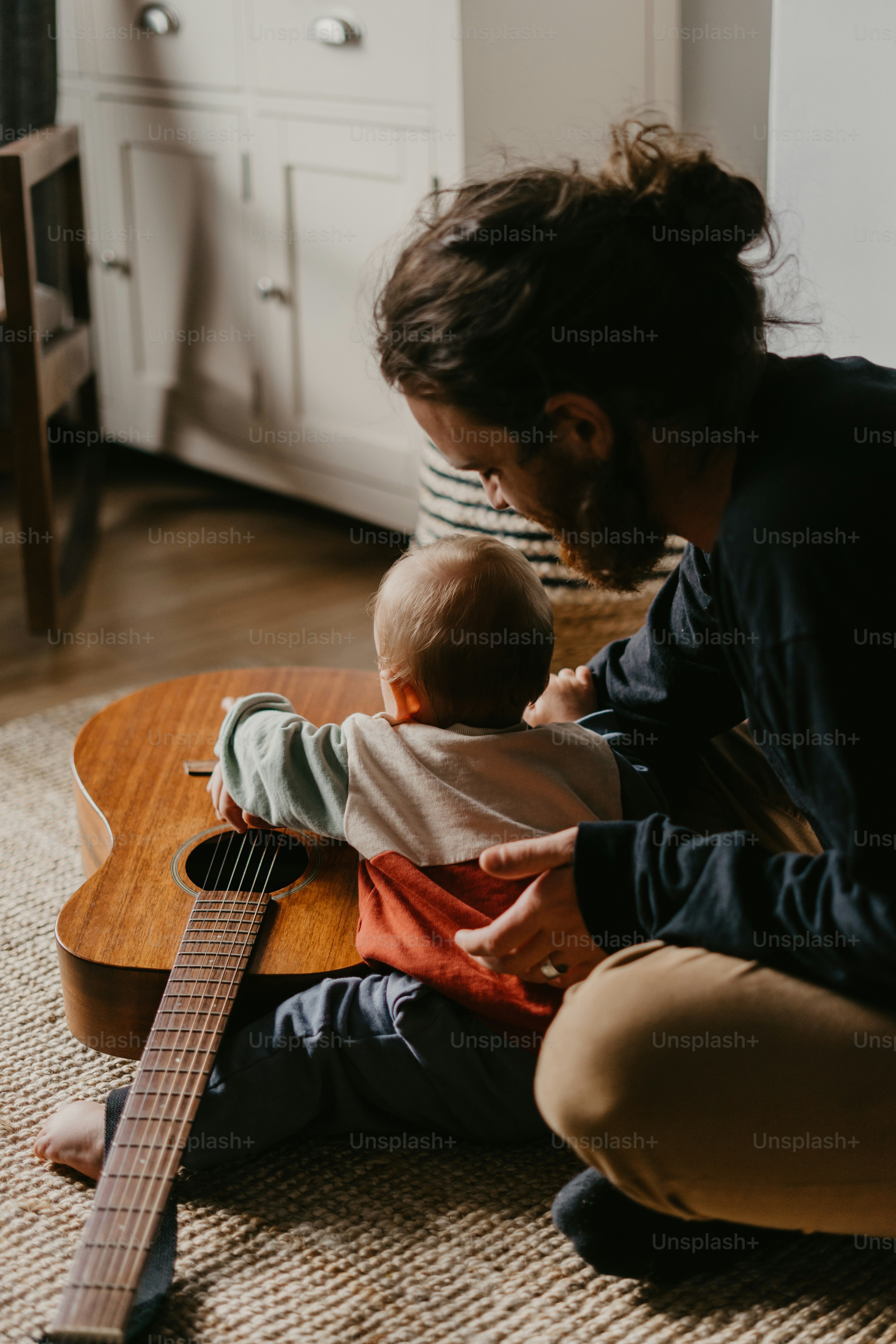 um homem segurando um bebê enquanto toca um violão