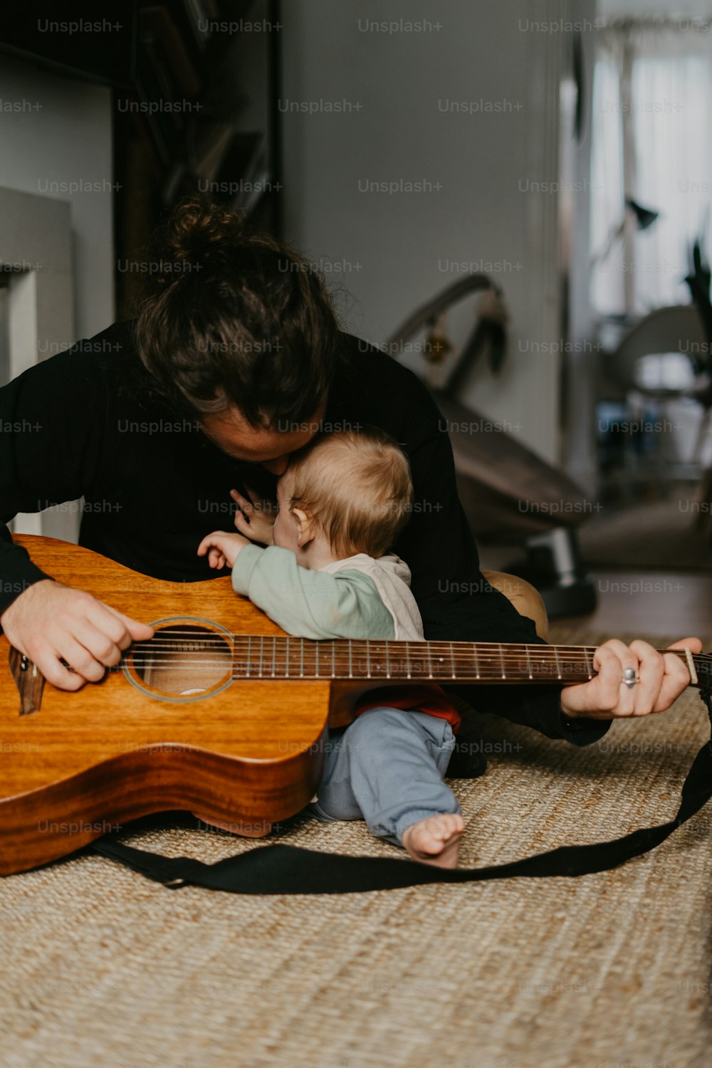 a woman holding a baby while playing a guitar