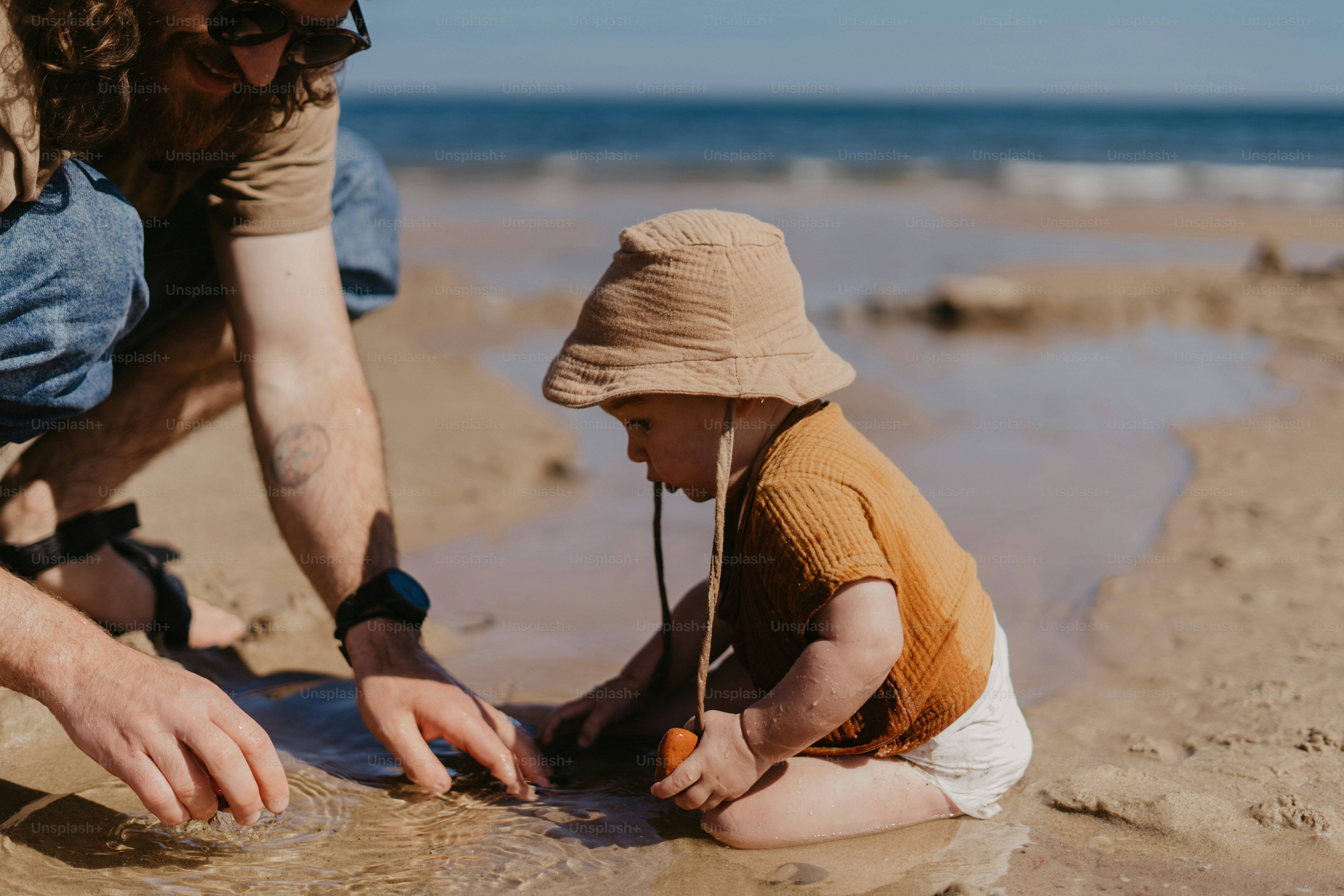a man and a child playing in the sand on the beach