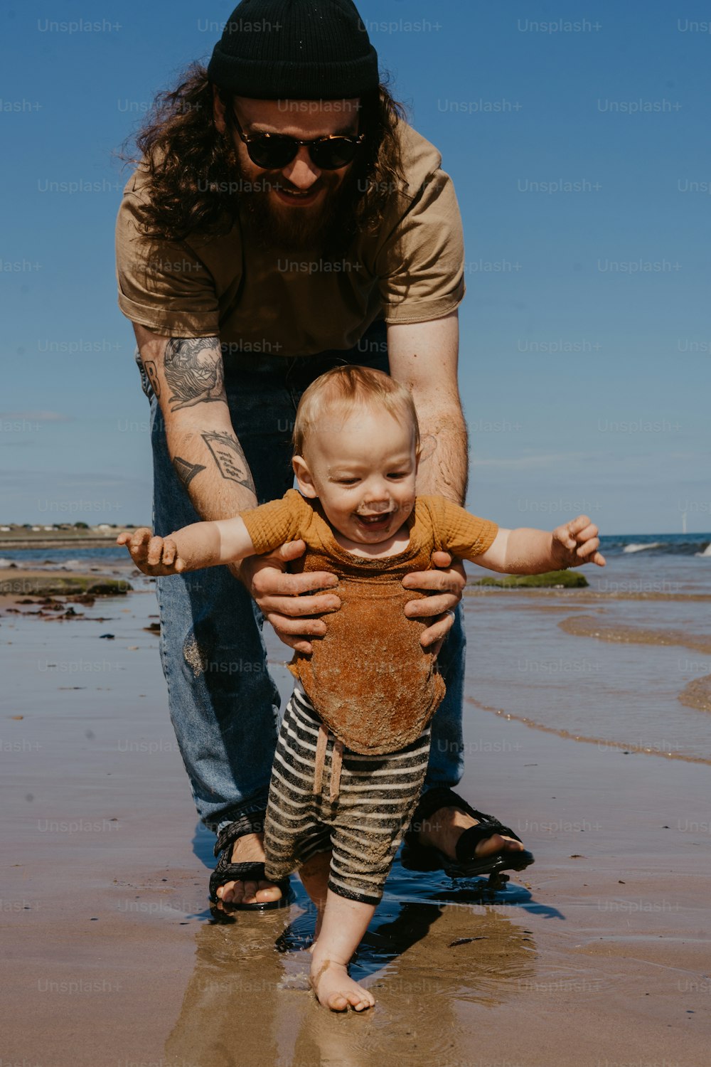 a man holding a baby on the beach