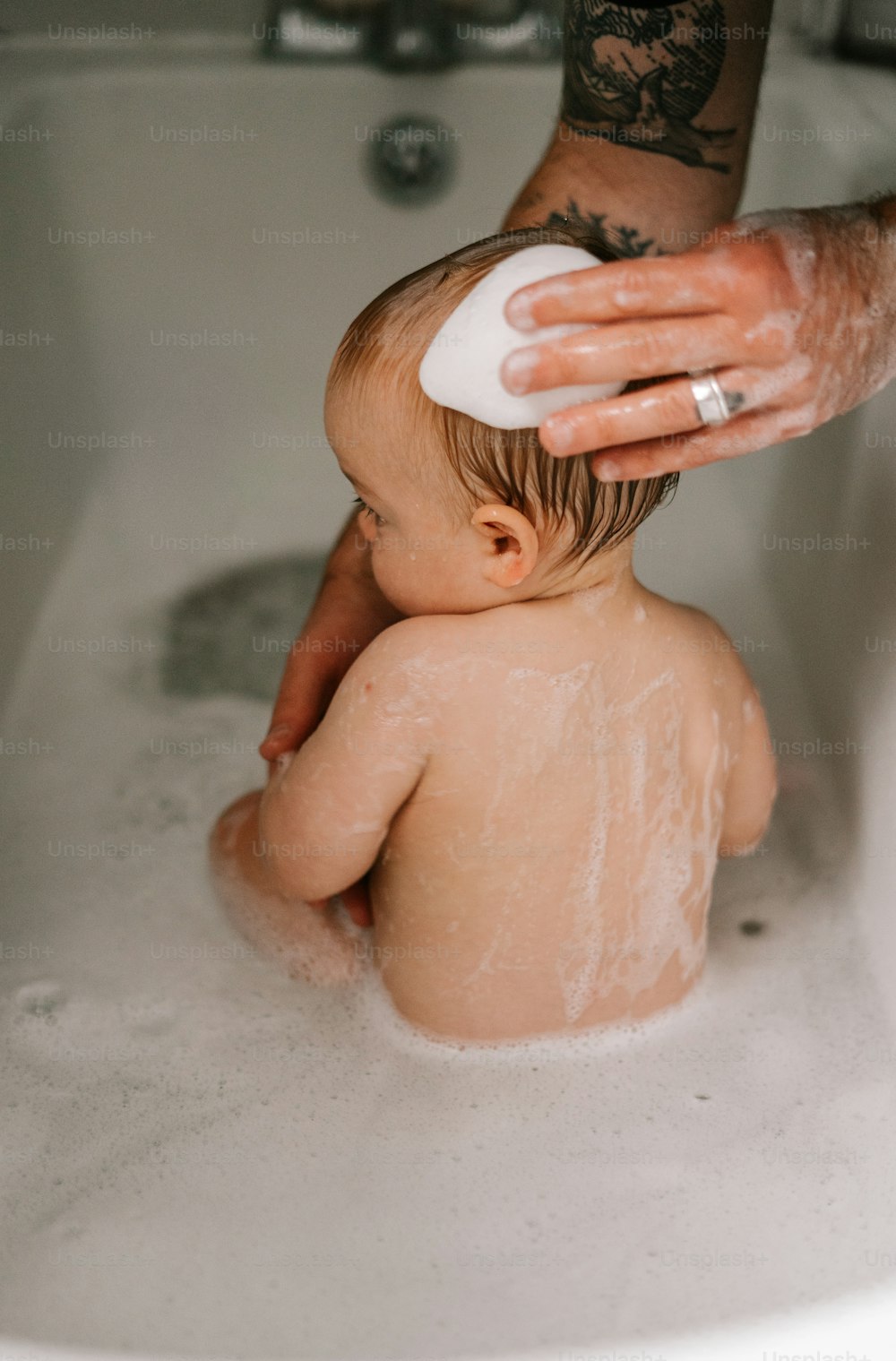 a baby sitting in a bathtub being bathed