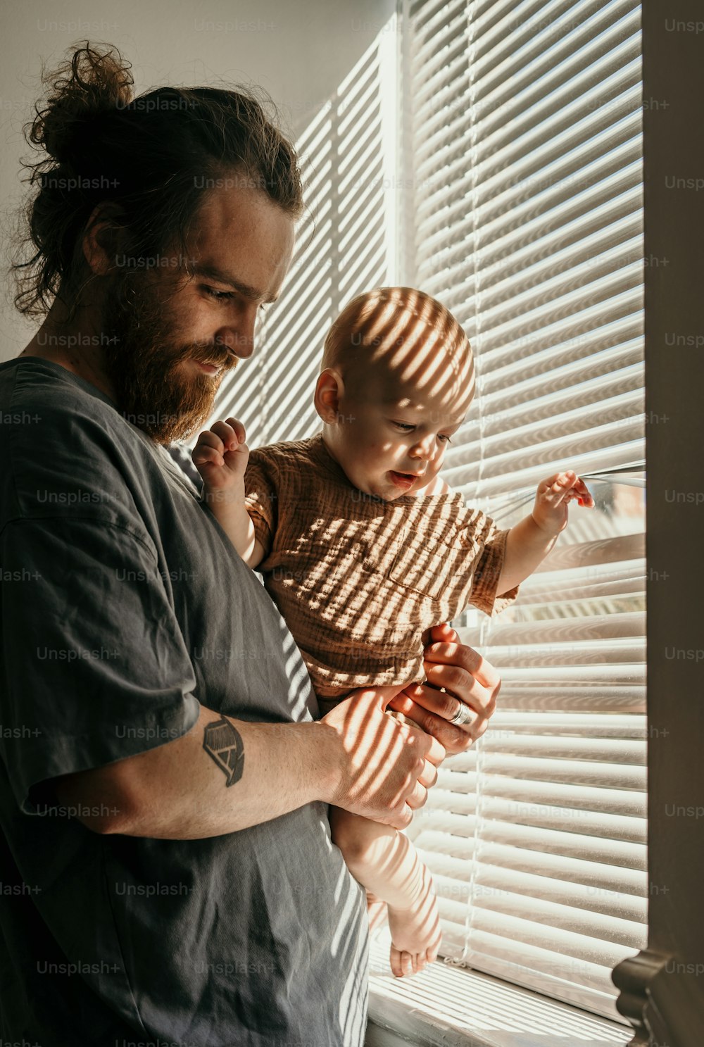 a man holding a baby in front of a window