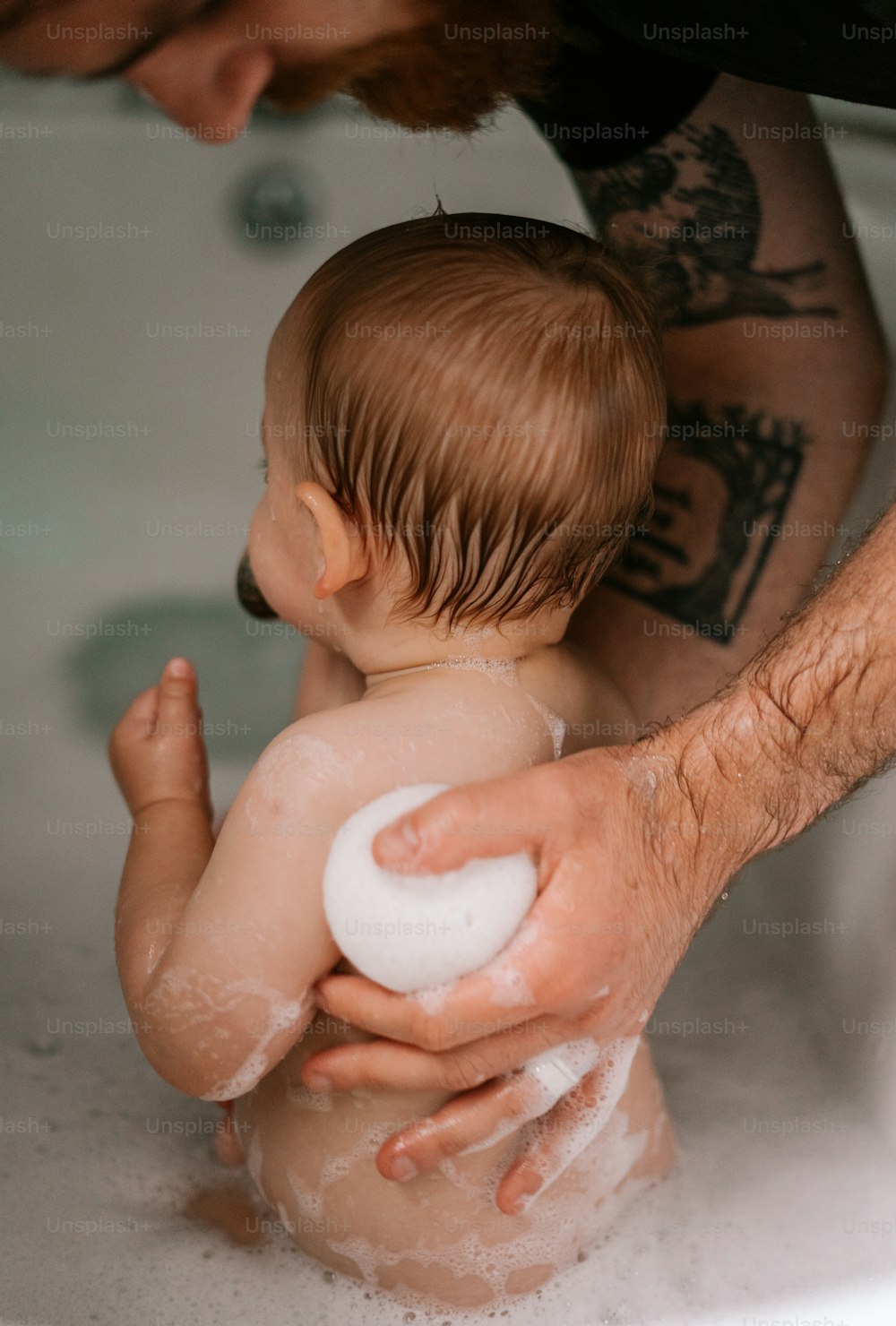 Ein Mann, der ein Baby in einer Badewanne hält