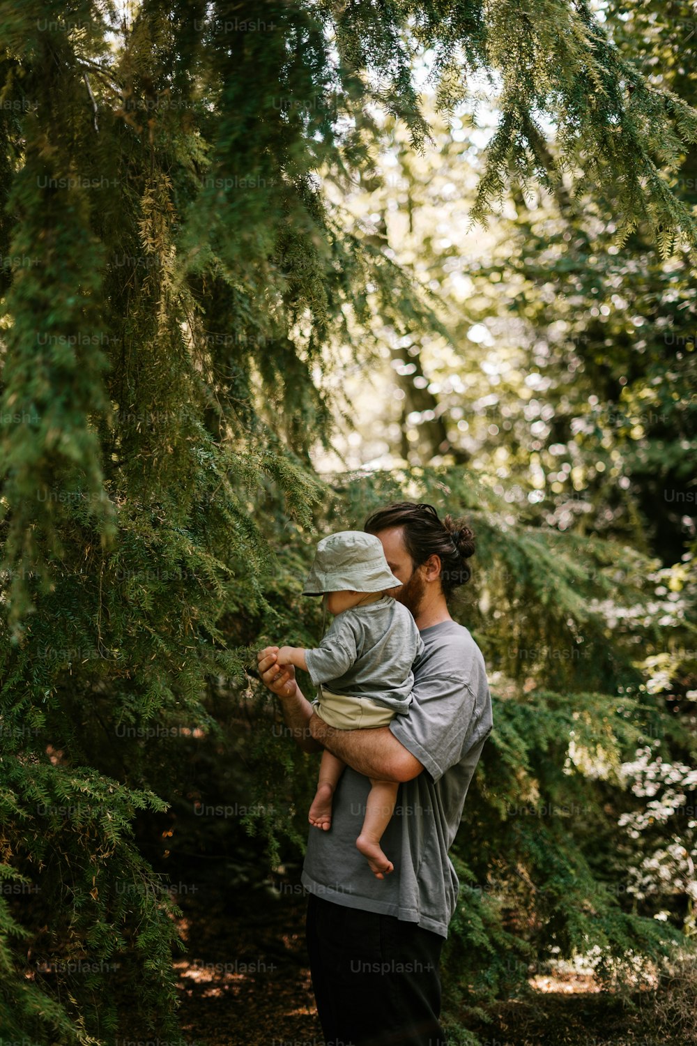 a man holding a baby in his arms in the woods