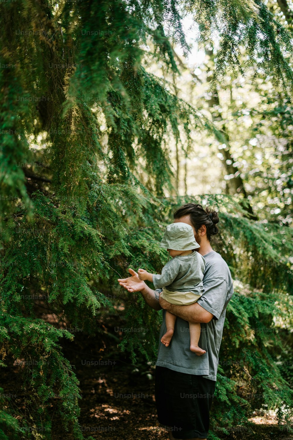 a man holding a child in his arms in the woods