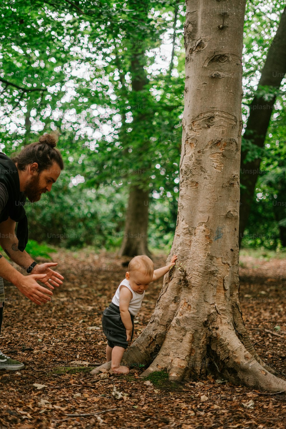a man and a baby standing next to a tree