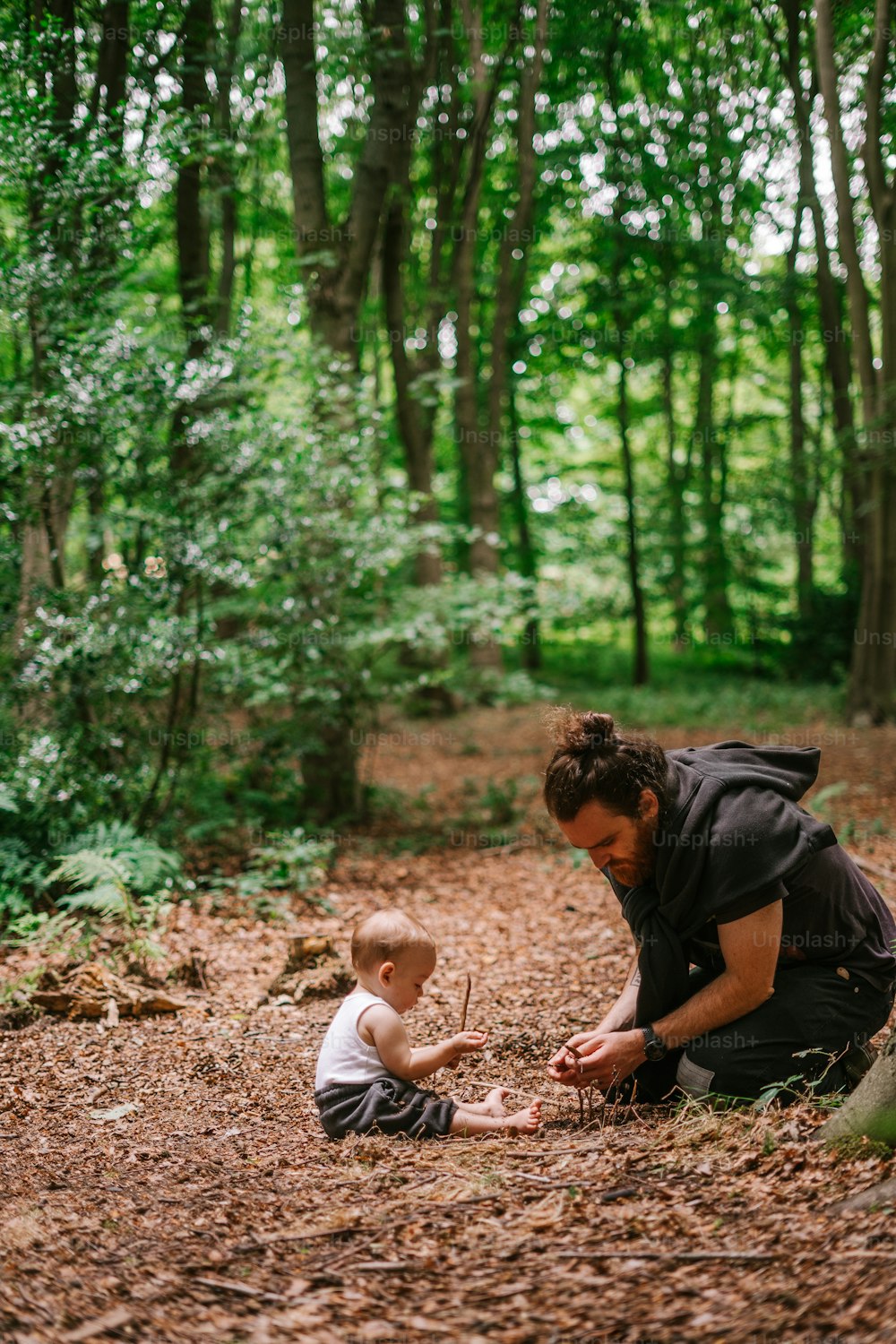 a woman kneeling down next to a baby in the woods