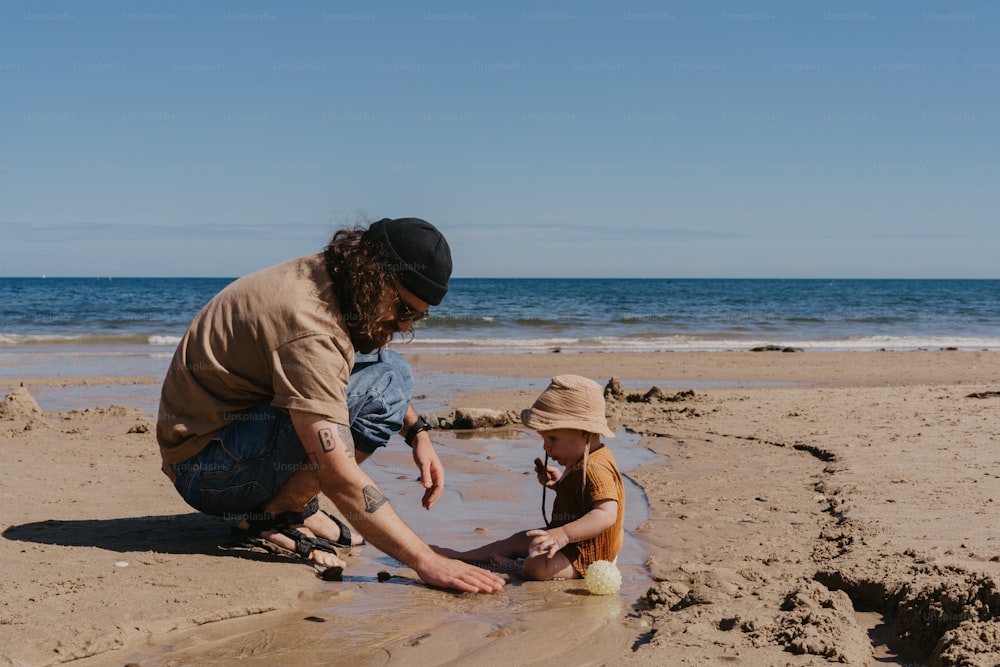 a man and a child playing in the sand at the beach