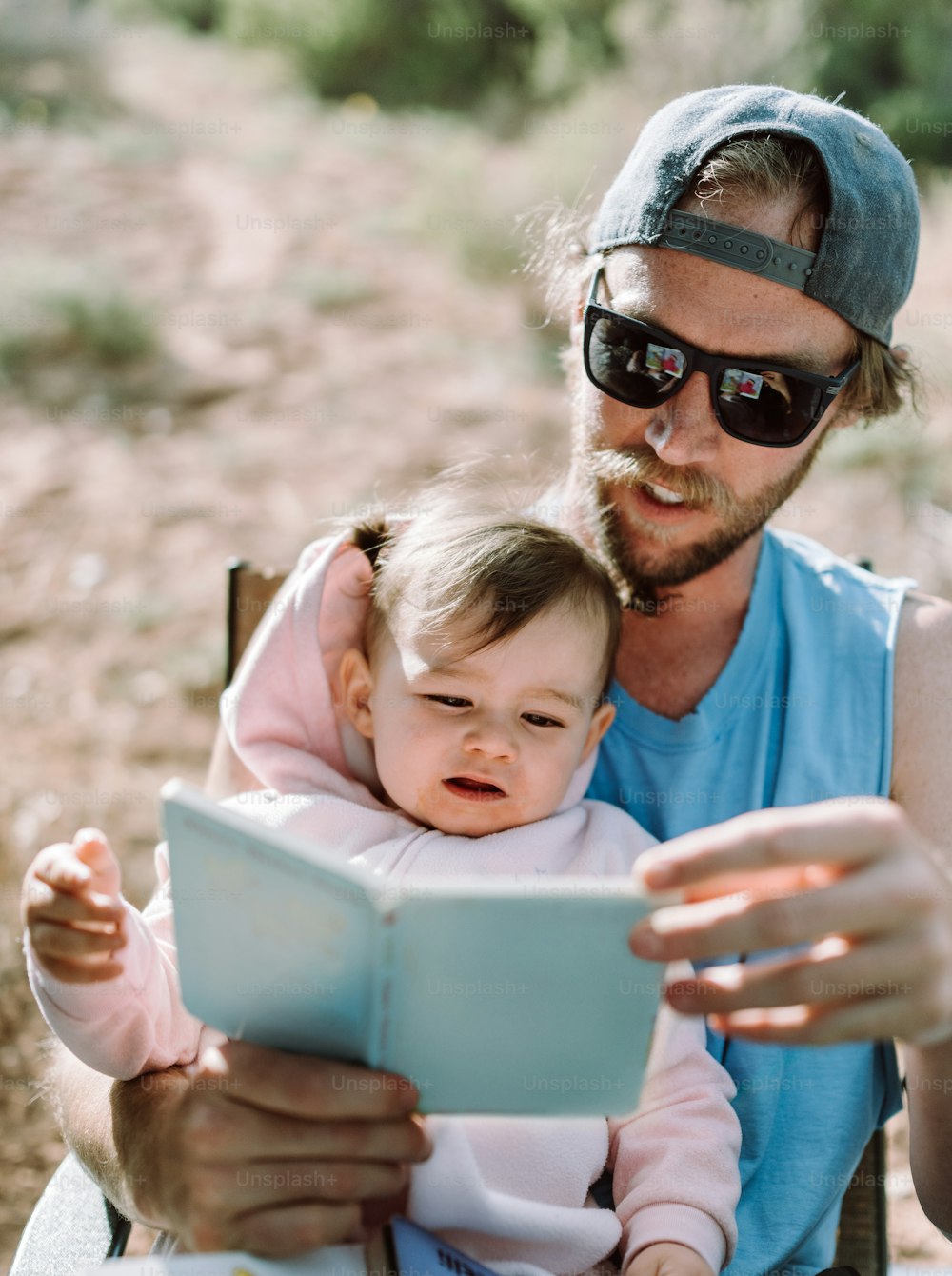 a man holding a baby while looking at a book