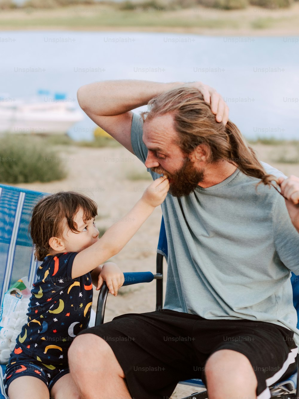 a man and a child sitting on a beach chair
