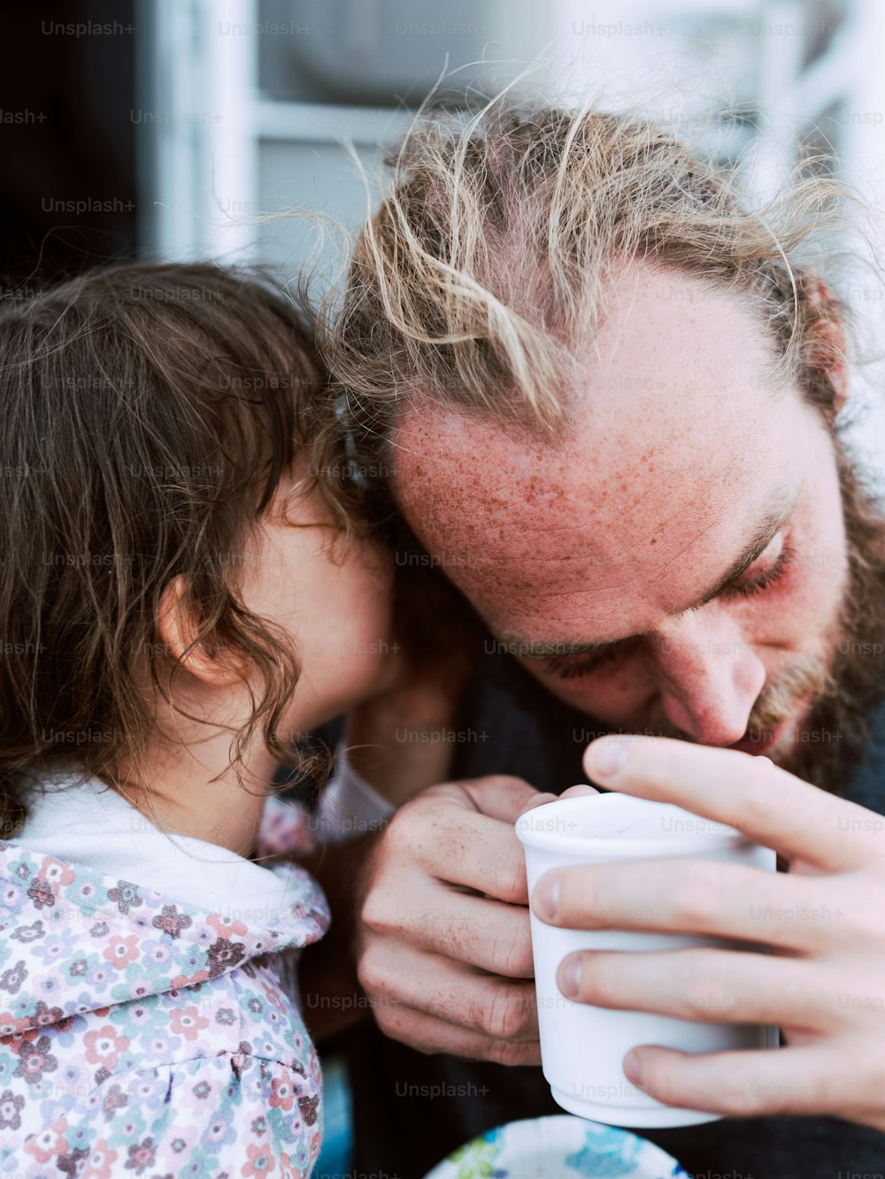 Ein Mann und ein kleines Mädchen, die aus einer Tasse trinken