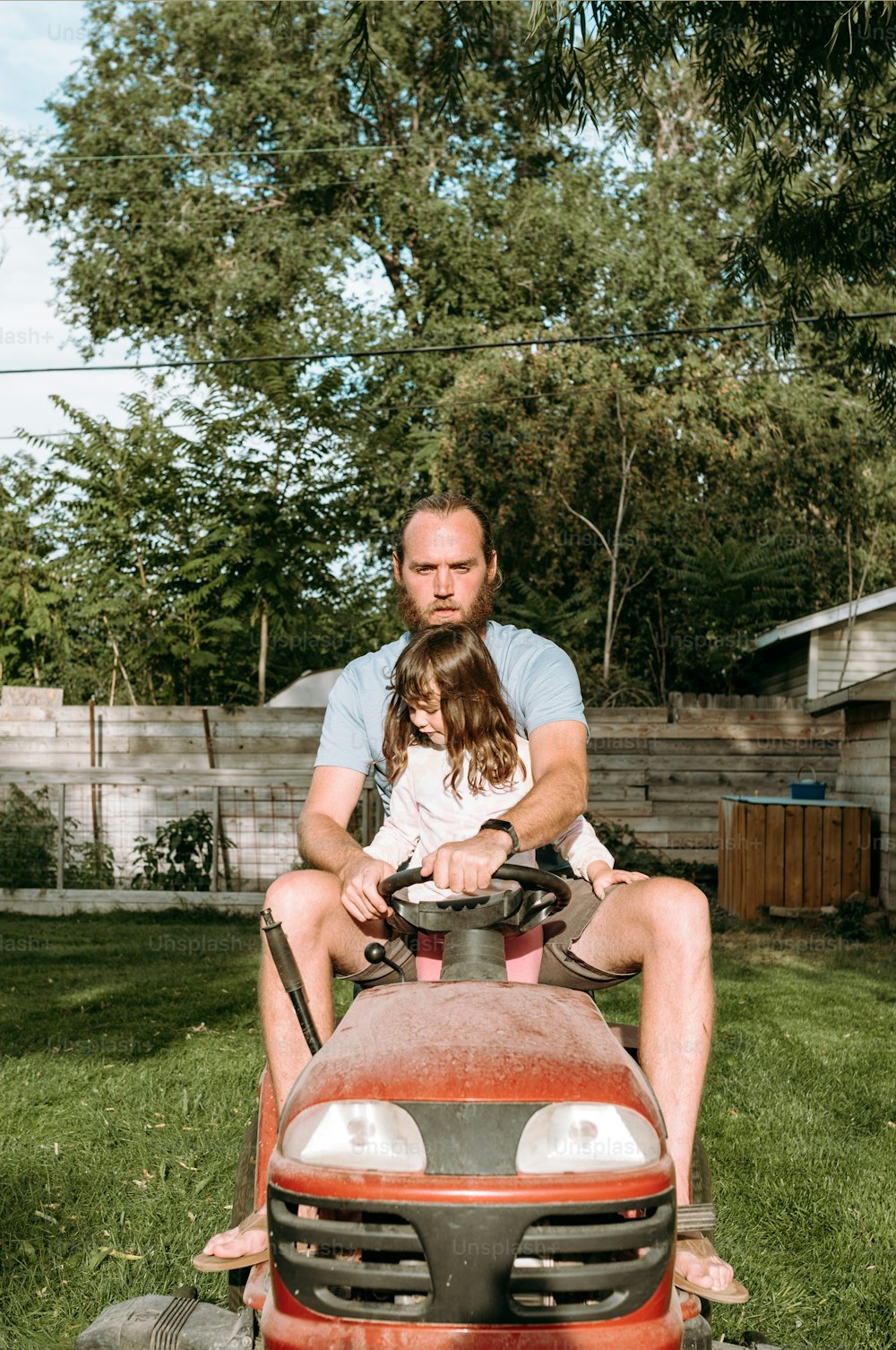 a man and a little girl sitting on a lawn mower