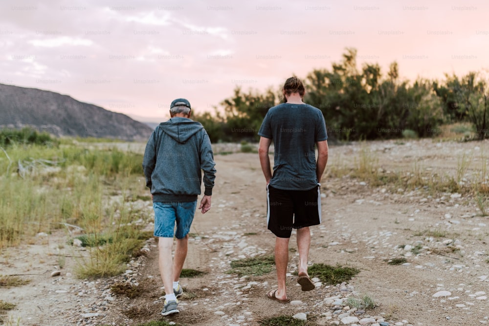 a couple of men walking down a dirt road