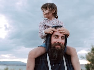 a man holding a little girl on his shoulders