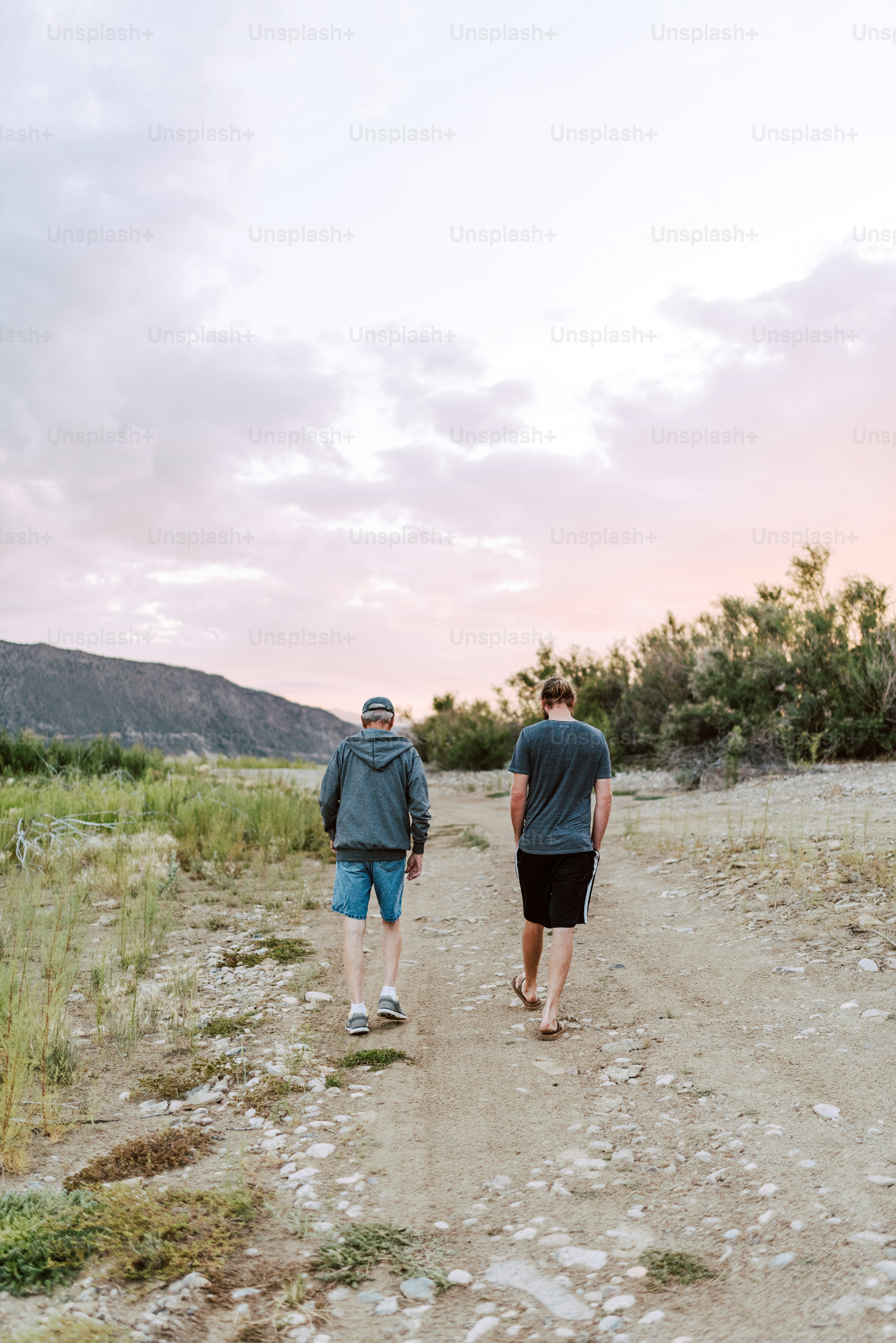 a couple of men walking down a dirt road