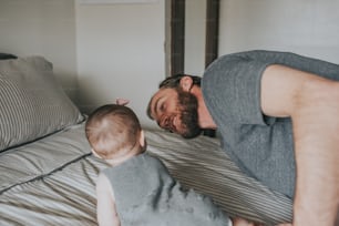 a man is playing with a baby on a bed