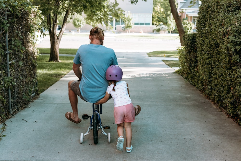 a man riding a bike with a little girl on it