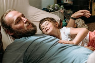 a man and a little girl laying on a bed