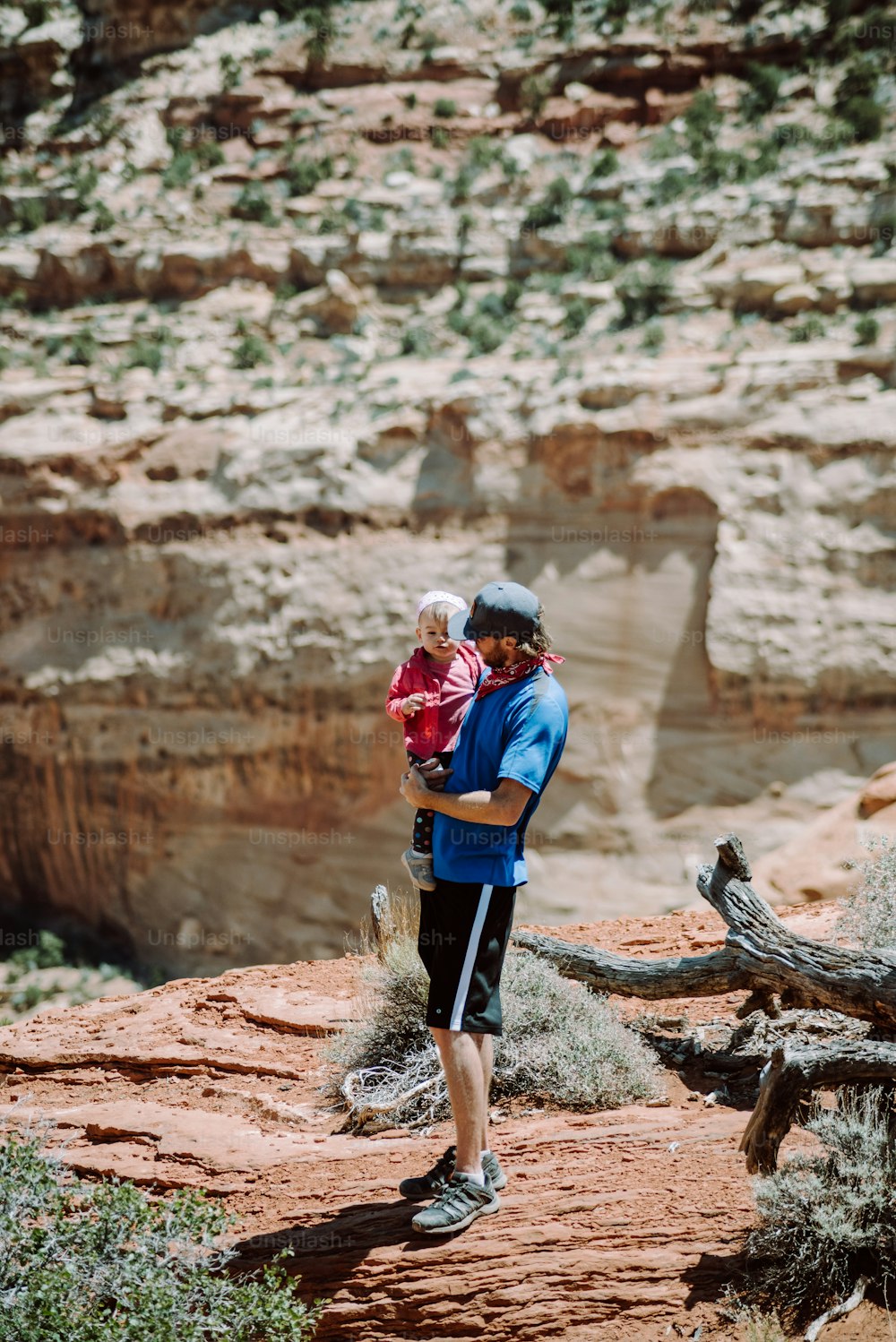 a man holding a baby in his arms while standing in the desert