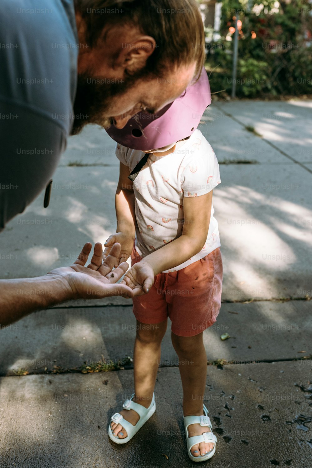 a man holding a small child's hand on a sidewalk