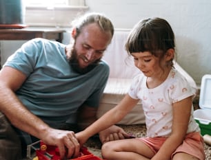 a man sitting next to a little girl on the floor