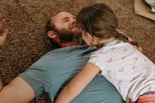 a man laying on the floor with a little girl