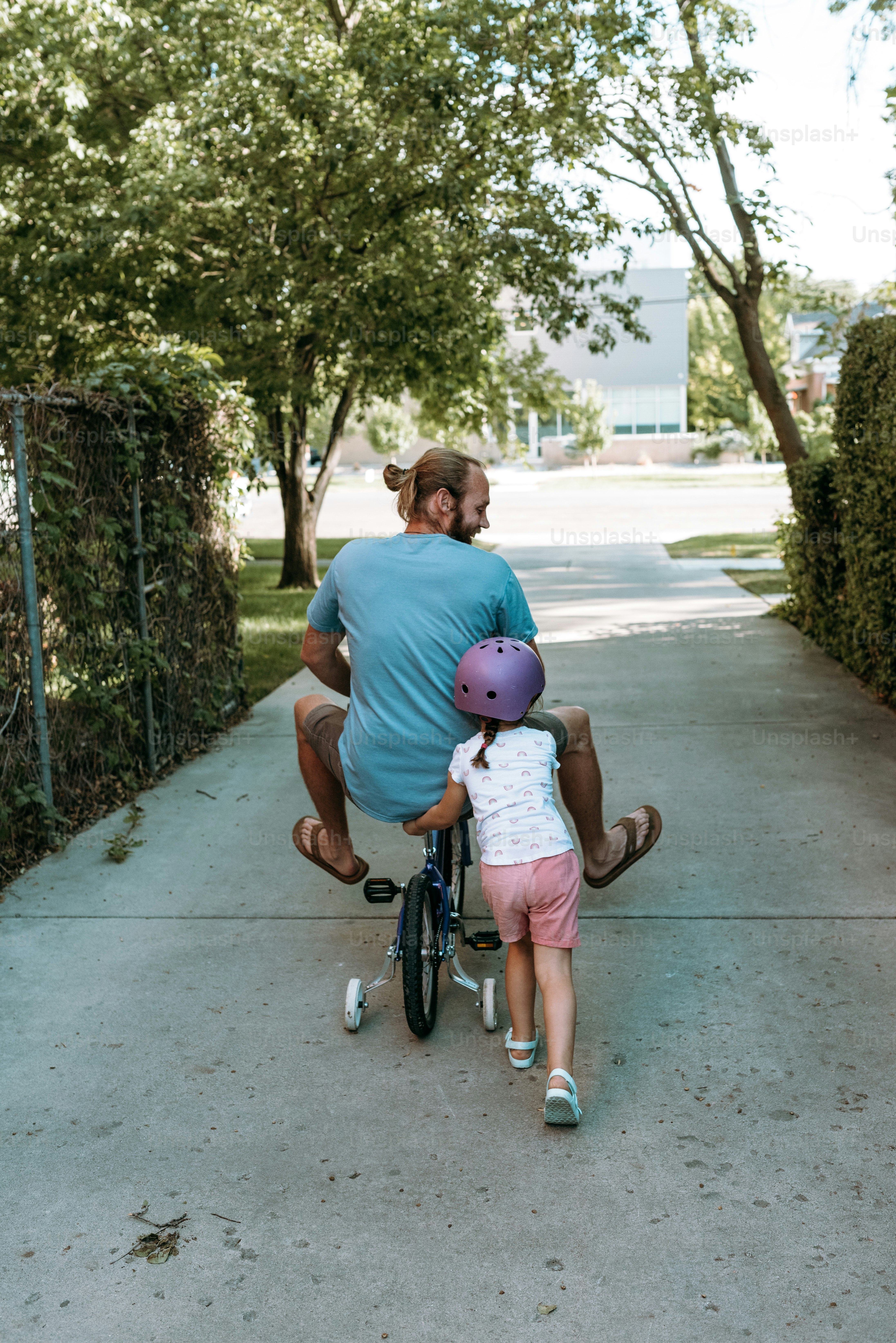 a man riding a bike with a little girl on the back of it
