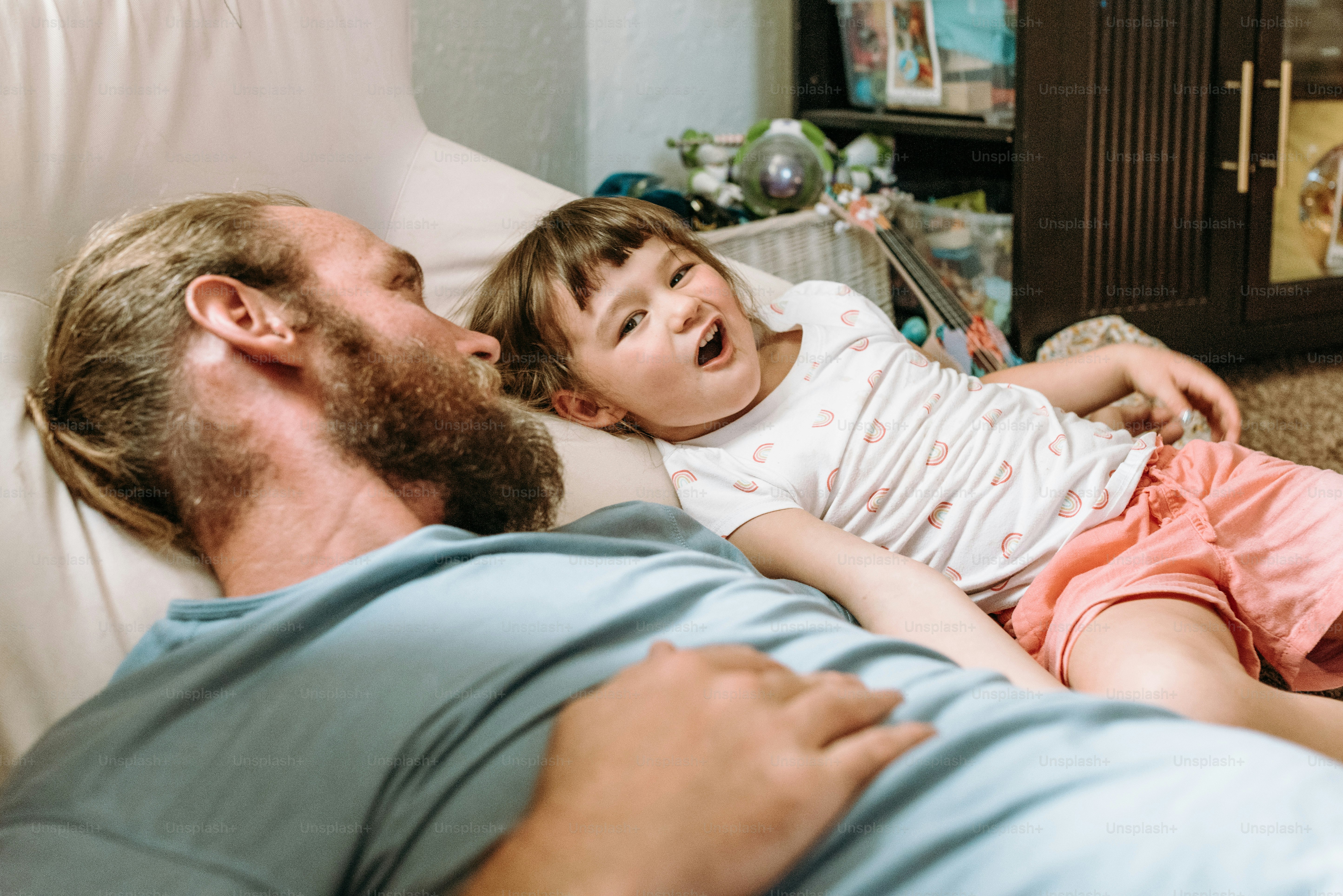 a man laying on a couch with a little girl