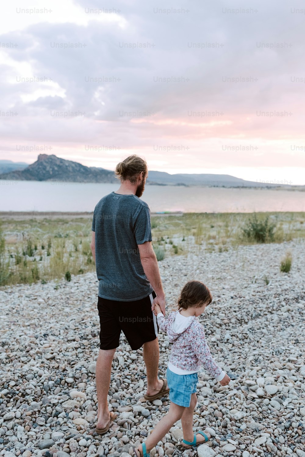 Un uomo e una bambina che camminano su una spiaggia rocciosa