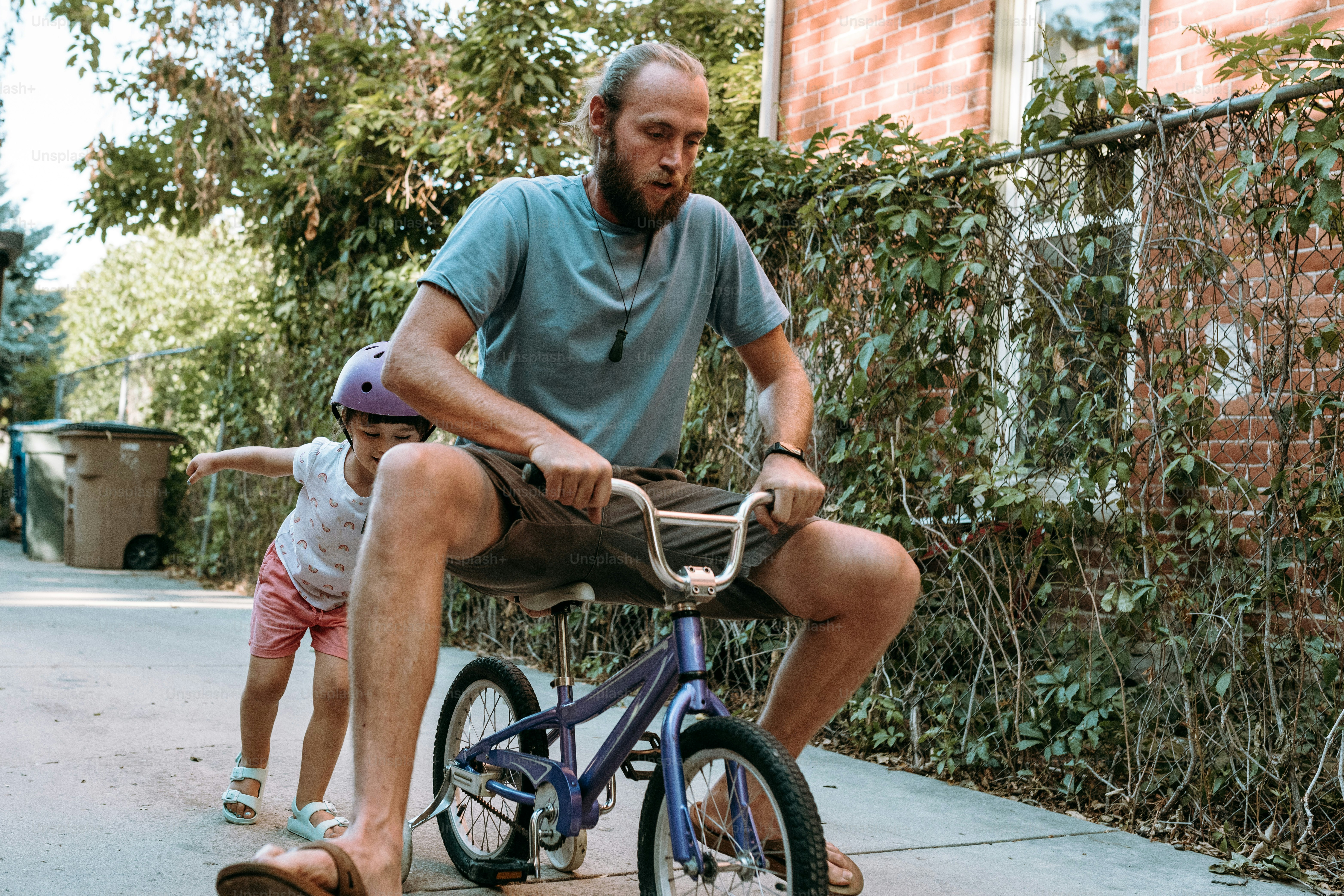 Un uomo che va in bicicletta accanto a una bambina