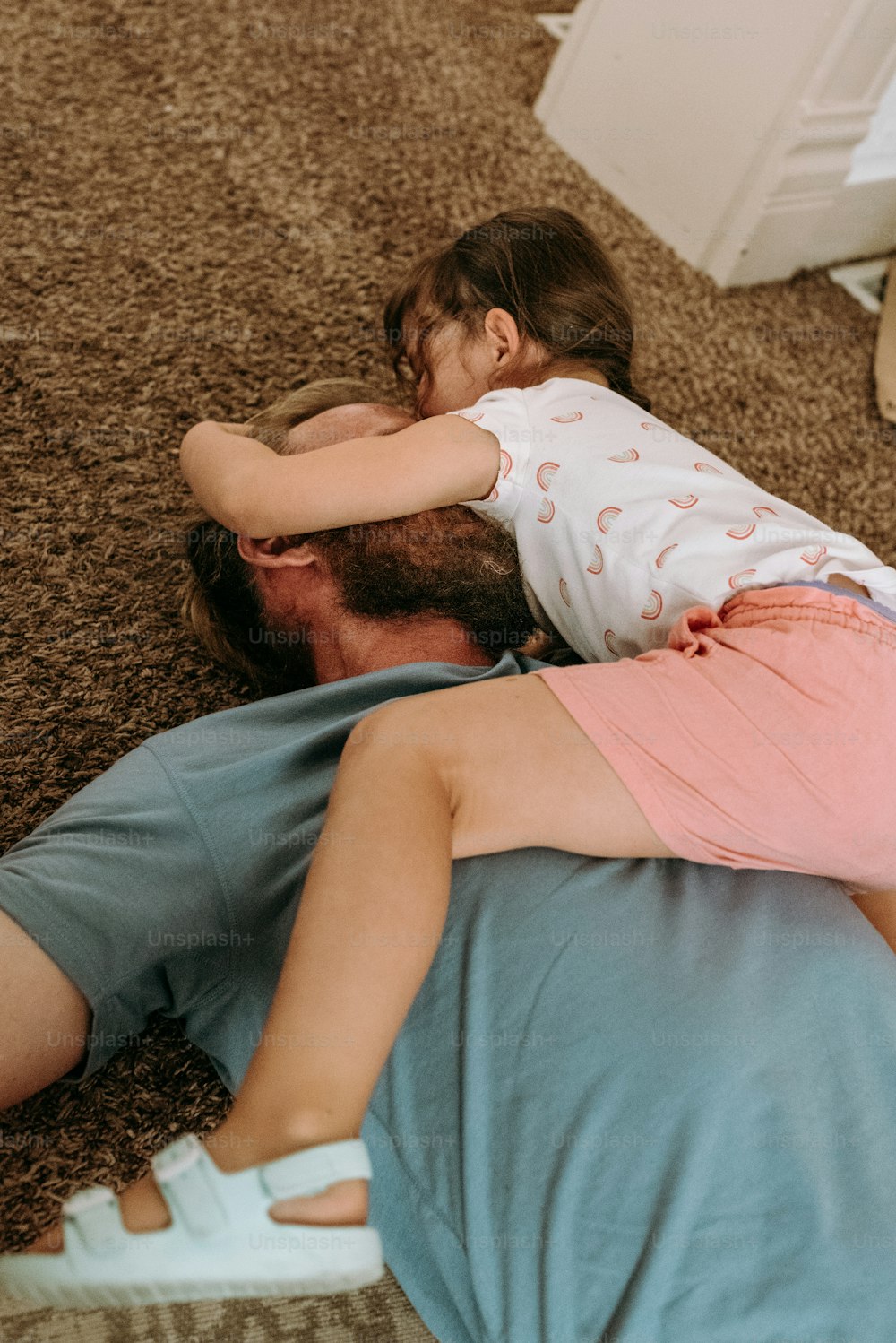 Ein Mann, der mit einem kleinen Mädchen auf dem Rücken auf dem Boden liegt